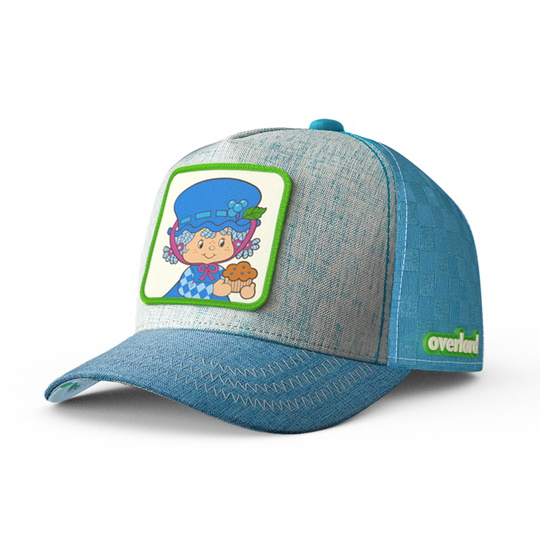 Trucker cap hat with a woven patch featuring the character Blueberry Muffin from Strawberry Shortcake on the front. The cap has a blue brim and a light blue crown.