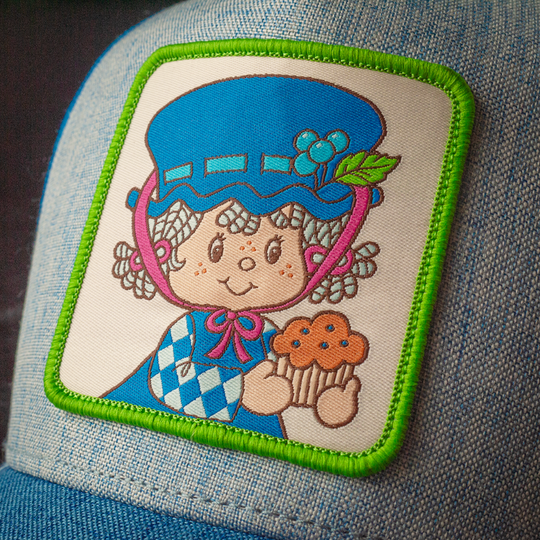 Close-up of Blueberry Muffin from Strawberry Shortcake woven patch on blue linen trucker cap hat