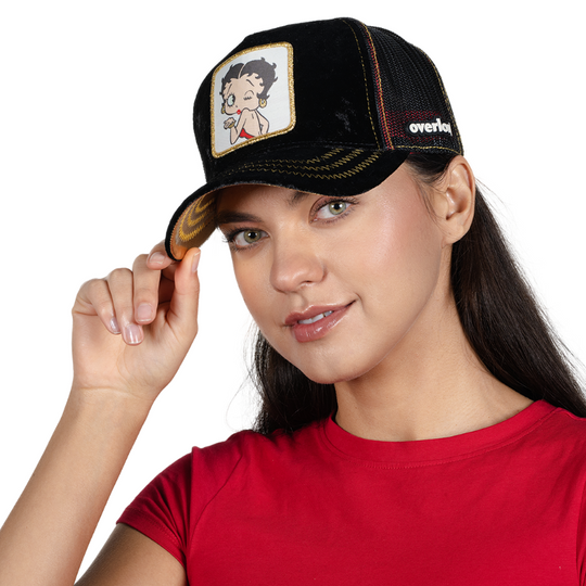Woman wearing black crushed velvet trucker cap featuring a woven patch of Betty Boop blowing a kiss attached to the crown.
