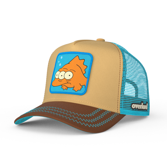 Tan and brown OVERLORD X The Simpsons Blinky the three-eyed fish trucker cap hat with aqua zig zag stitching. PVC Overlord logo.