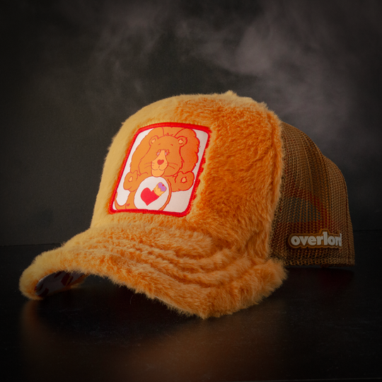 Orange plush trucker cap hat with Braveheart Lion woven patch against a black background