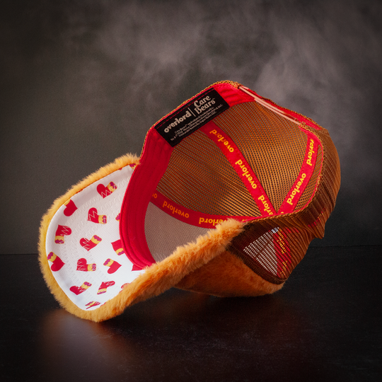 Inside view of orange plush trucker cap hat with Braveheart Lion belly symbol patterned fabric on underbrim