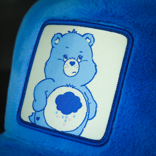 Close-up of a woven patch of Grumpy Bear from Care Bears attached to the crown.