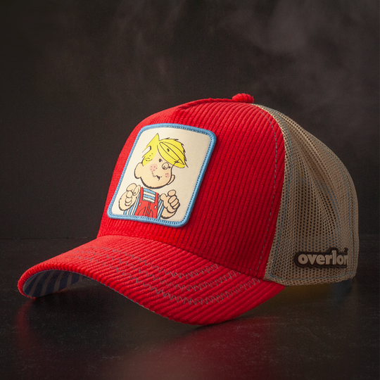 Red corduroy trucker cap hat with Dennis the Menace woven patch against a black background