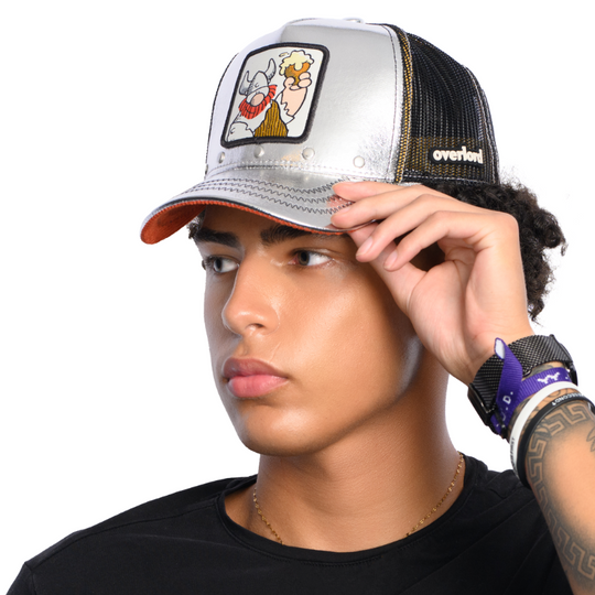 Man wearing a metallic silver trucker cap hat with Hagar the Horrible woven patch against a white background