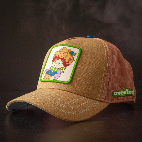 Brown linen trucker cap hat with Huckleberry Pie from Strawberry Shortcake on woven patch against a black background