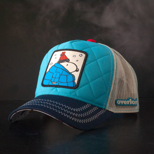 Quilted blue trucker cap hat with Peanuts Snoopy in blue jacket woven patch against a black background
