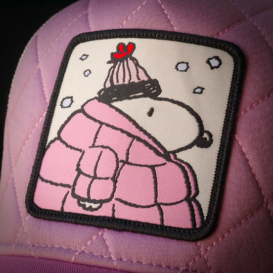 Close-up of Peanuts Snoopy in pink jacket woven patch on quilted pink trucker cap hat
