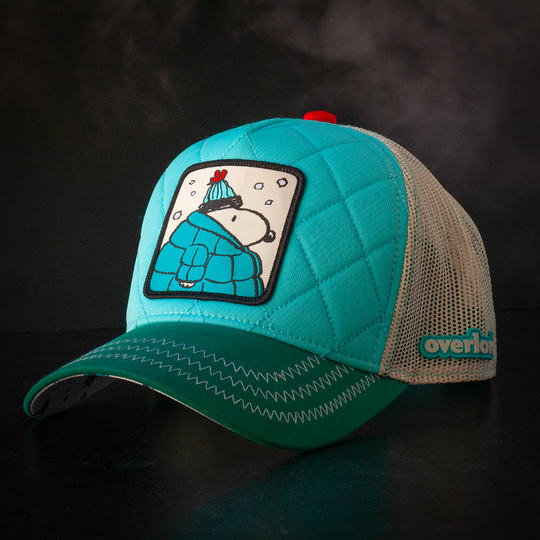 Quilted turquoise and teal trucker cap hat with Peanuts Snoopy in teal jacket woven patch against a black background