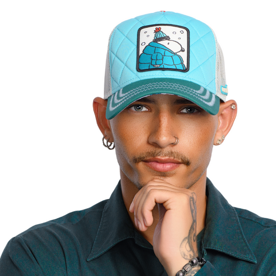 Man wearing a quilted turquoise and teal trucker cap hat with Peanuts Snoopy in teal jacket woven patch against a white background