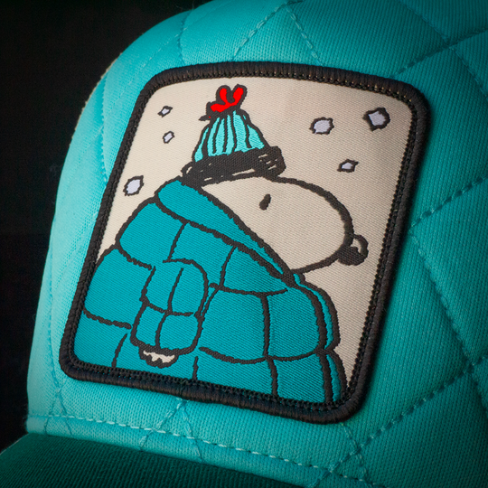 Close-up of Peanuts Snoopy in teal jacket woven patch on quilted turquoise trucker cap hat.