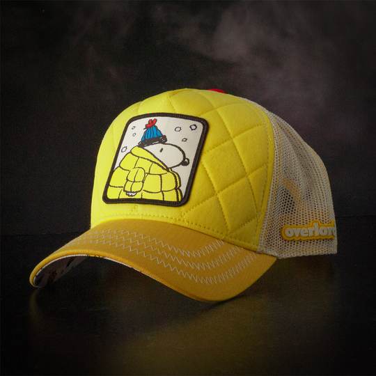 Quilted yellow trucker cap hat with Snoopy in Jacket woven patch against a black background