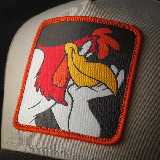 Close-up of Foghorn Leghorn patch on a beige and brown trucker cap.