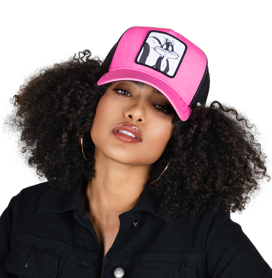 Woman wearing hot pink twill trucker cap with black mesh featuring a woven patch of Penelope the Cat from the Looney Tunes attached to the crown.