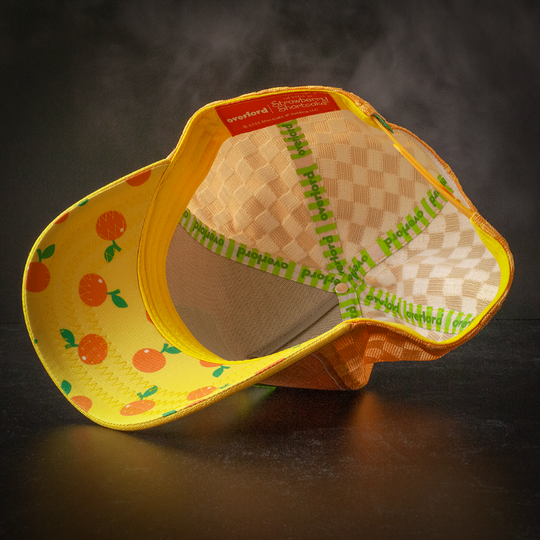 Inside view of orange and yellow linen trucker cap hat with scattered oranges printed on underbrim