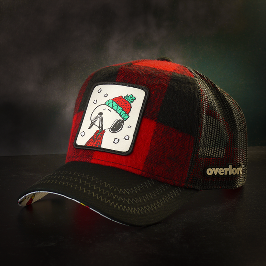 Red and black buffalo plaid flannel trucker cap with black mesh featuring a woven patch of Lumberjack Snoopy from the Peanuts attached to the crown.