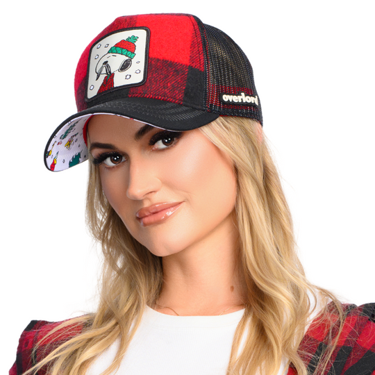 Woman wearing red and black buffalo plaid flannel trucker cap with black mesh featuring a woven patch of Lumberjack Snoopy from the Peanuts attached to the crown.