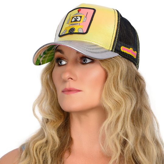 Woman wearing metallic yellow and silver trucker cap hat featuring Plex from Yo Gabba Gabba on woven patch attached to crown