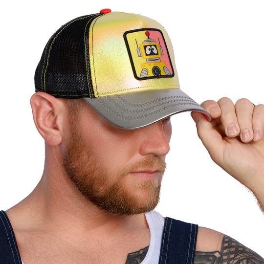 Man wearing metallic yellow and silver trucker cap hat featuring Plex from Yo Gabba Gabba on woven patch attached to crown