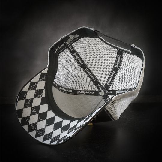 Inside view of shiny black  faux leather trucker cap with black and white diamond pattern on underbrim