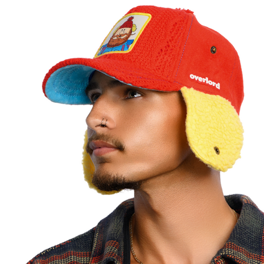 Person wearing a colorful hat with ear flaps and a cartoon character patch on a white background