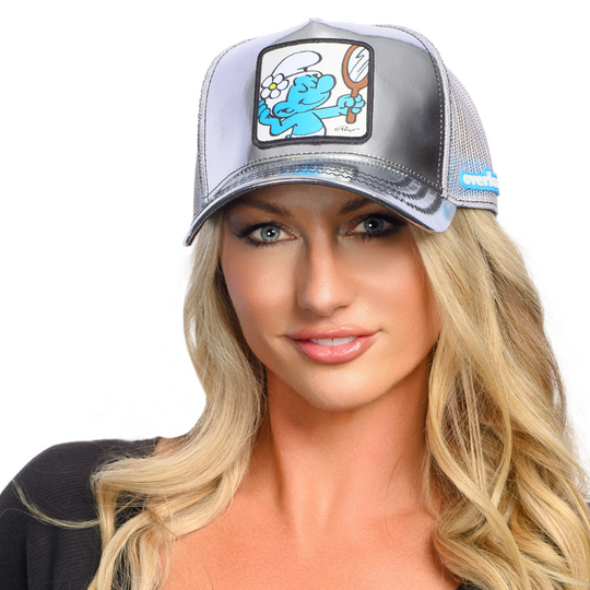 Woman wearing a metallic silver trucker cap with Vanity Smurf patch against a white background