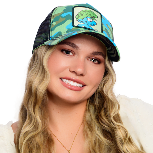 Woman wearing turquoise and green camo trucker cap with black mesh featuring a woven patch of Wild Smurf from the Smurfs attached to the crown