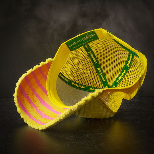 Inside view of yellow faux fur trucker cap hat with pink and orange striped underbrim