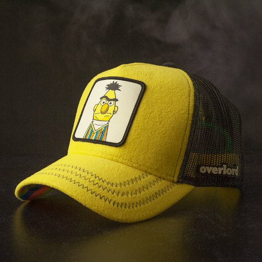 Yellow fleece trucker cap hat with Sesame Street Bert woven patch against a black background