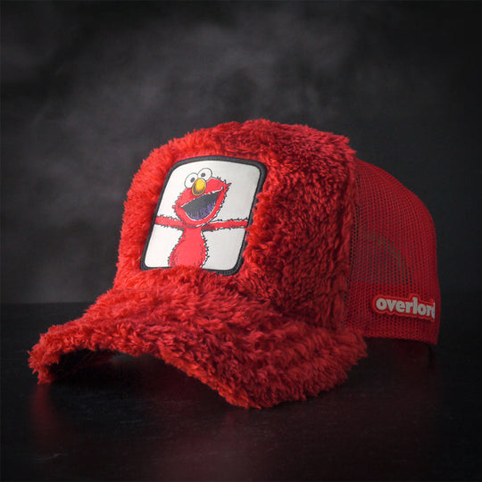 Red faux fur trucker cap hat featuring Elmo from Sesame Street on woven patch attached to crown against a black background