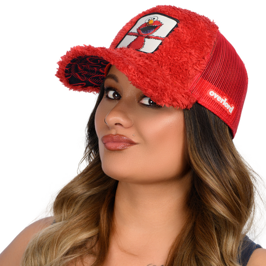 Woman wearing red faux fur trucker cap hat featuring Elmo from Sesame Street on woven patch attached to crown