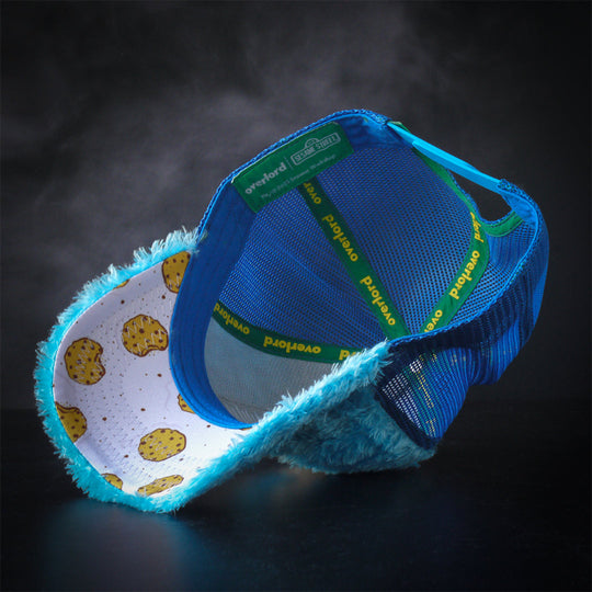Inside view of turquoise faux fur trucker cap hat with cookies and cookie crumbs printed on underbrim