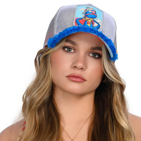 Woman wearing metallic silver and blue faux fur trucker cap hat featuring Super Grover from Sesame Street on woven patch attached to crown