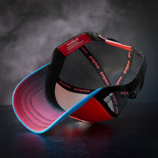 Inside view of red and blue trucker cap hat with black and red grid pattern printed on underbrim