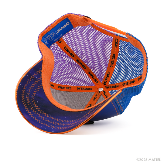 Underside of the Two-Bad from Masters of the Universe retro trucker cap, showing a blue starry-print brim, blue Masters of the Universe tag, purple and blue mesh crown, and orange Overlord branded taping with black text.