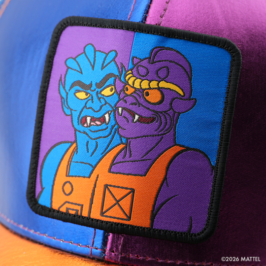 Woven patch of Two-Bad from Masters of the Universe with two fanged faces, one blue and one purple, on a split blue and purple background with black border, stitched onto the metallic purple retro trucker cap.