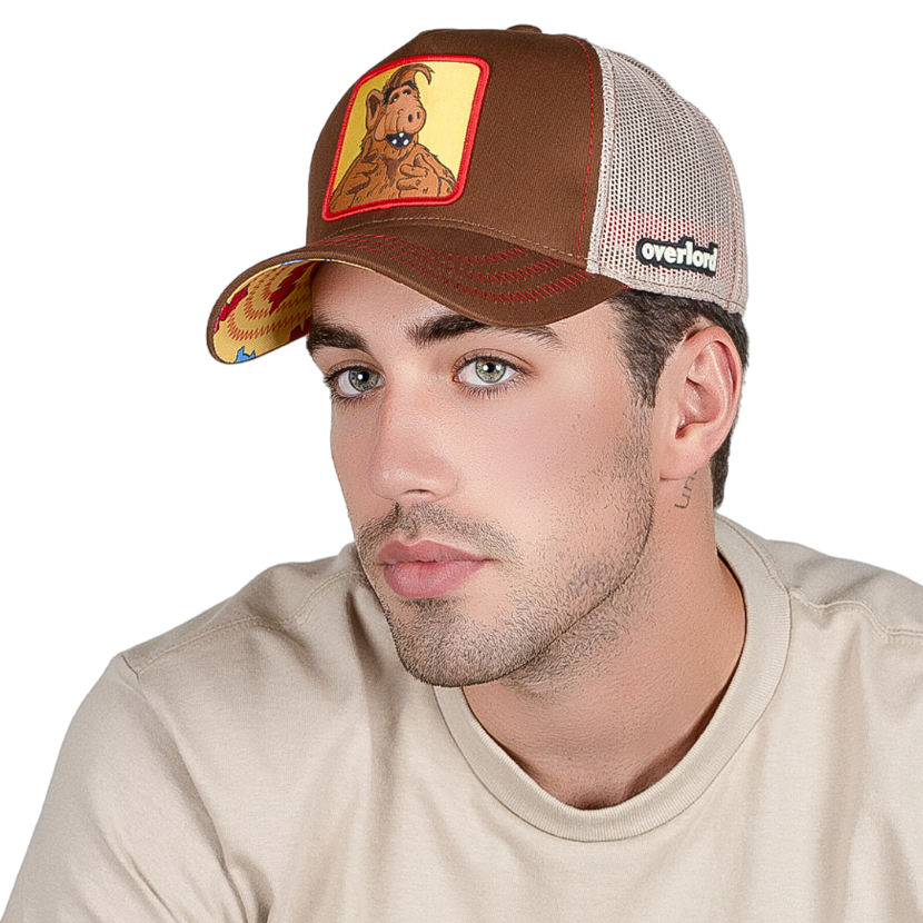 Man wearing brown twill trucker cap with khaki mesh featuring a woven patch of ALF attached to the crown.
