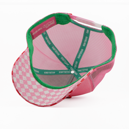 Underside of the Amy Rose from Sonic the Hedgehog retro trucker cap, showing a pink and white argyle-pattern brim, Sonic the Hedgehog tag, pink mesh crown, and green Overlord branded taping with white text.