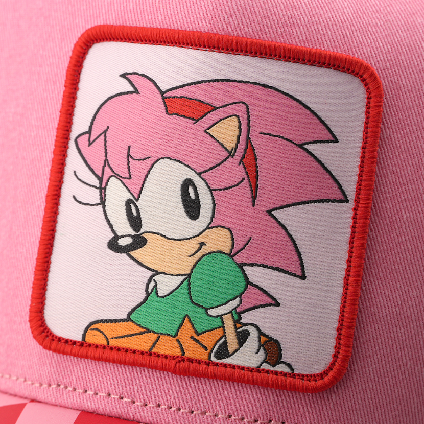 Woven patch of Amy Rose from Sonic the Hedgehog wearing a green top, set against a white background with red border, stitched onto the pink retro trucker cap.