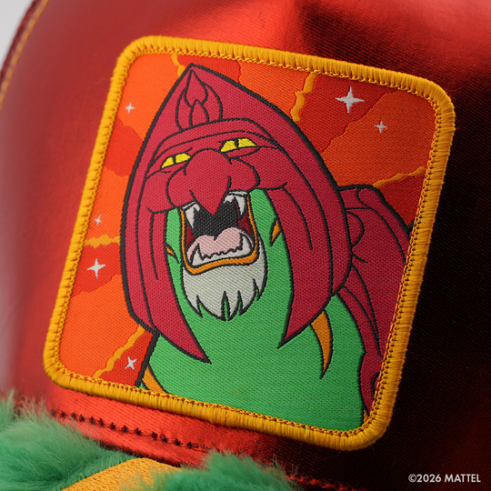 Woven patch of Battle Cat from Masters of the Universe with a roaring green face and dark red mane, set against an orange starry background with gold border, stitched onto the metallic red retro trucker cap.