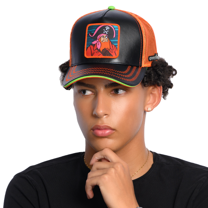 Man wearing black faux leather trucker cap with orange mesh featuring a woven patch of Red Beard villain from Scooby Doo attached to the crown.