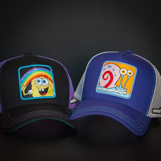 Black OVERLORD X SpongeBob Imagination SpongeBob holding a rainbow trucker baseball cap hat with purple stitching. PVC Overlord logo.