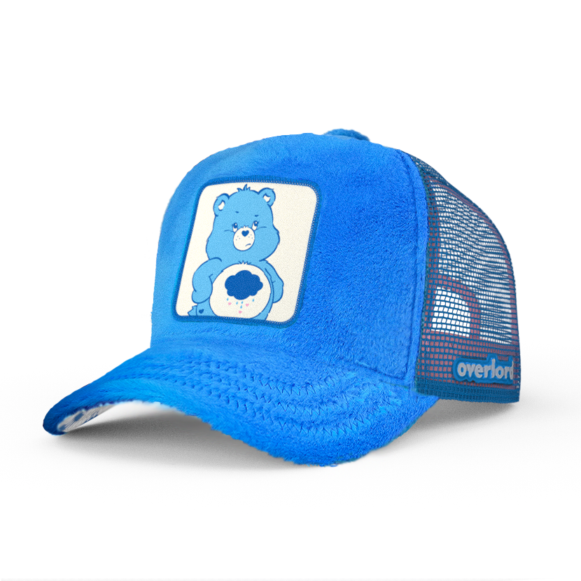 Blue faux fur trucker cap with blue mesh featuring a woven patch of Grumpy Bear from Care Bears attached to the crown.