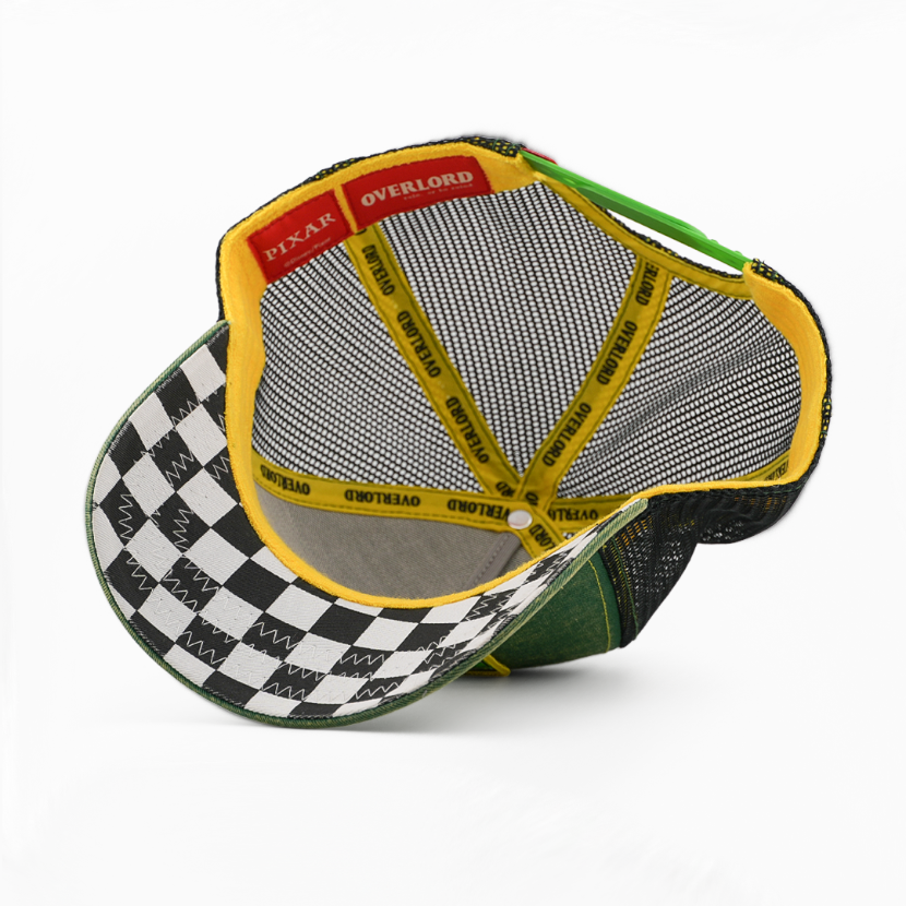 An overhead view of a snapback cap showing its interior. The cap features a black and white checkered pattern on the brim, a green mesh back, yellow trim, and red and yellow interior labels with text including 'PIXAR' and 'OVERLOADED'.