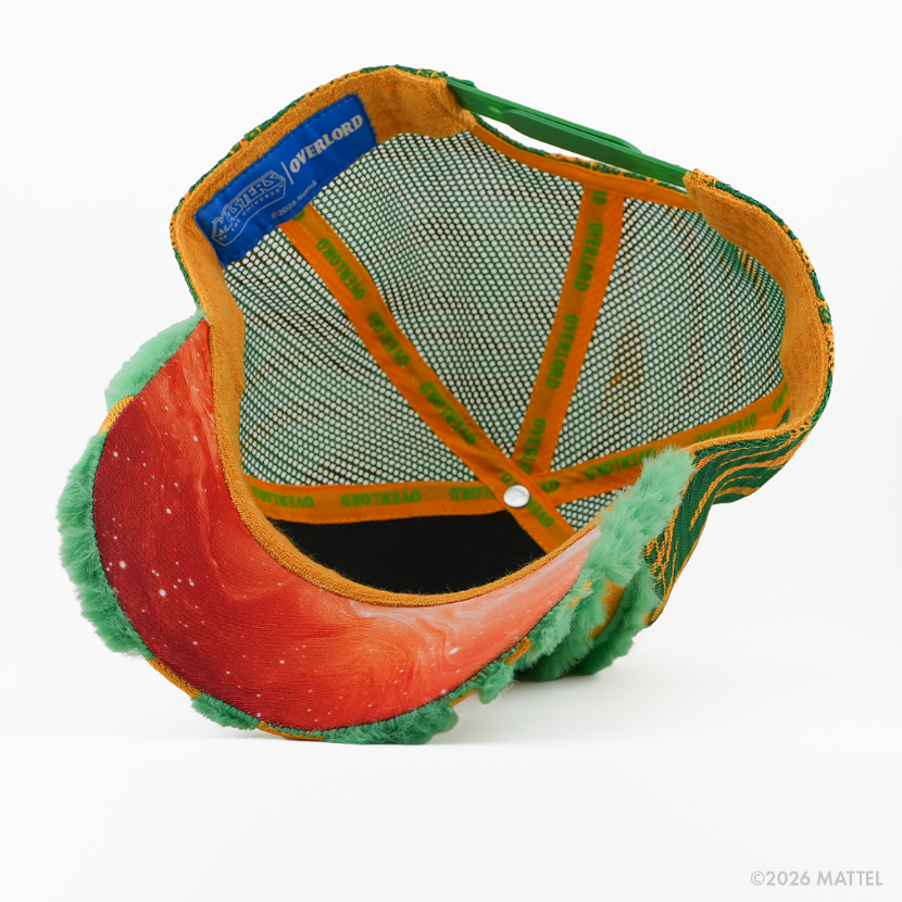 Underside of the Cringer from Masters of the Universe retro trucker cap, showing a red starry-print brim, blue Masters of the Universe tag, green mesh crown, and gold Overlord branded taping with green text.