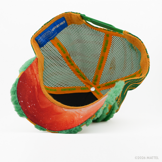Underside of the Cringer from Masters of the Universe retro trucker cap, showing a red starry-print brim, blue Masters of the Universe tag, green mesh crown, and gold Overlord branded taping with green text.