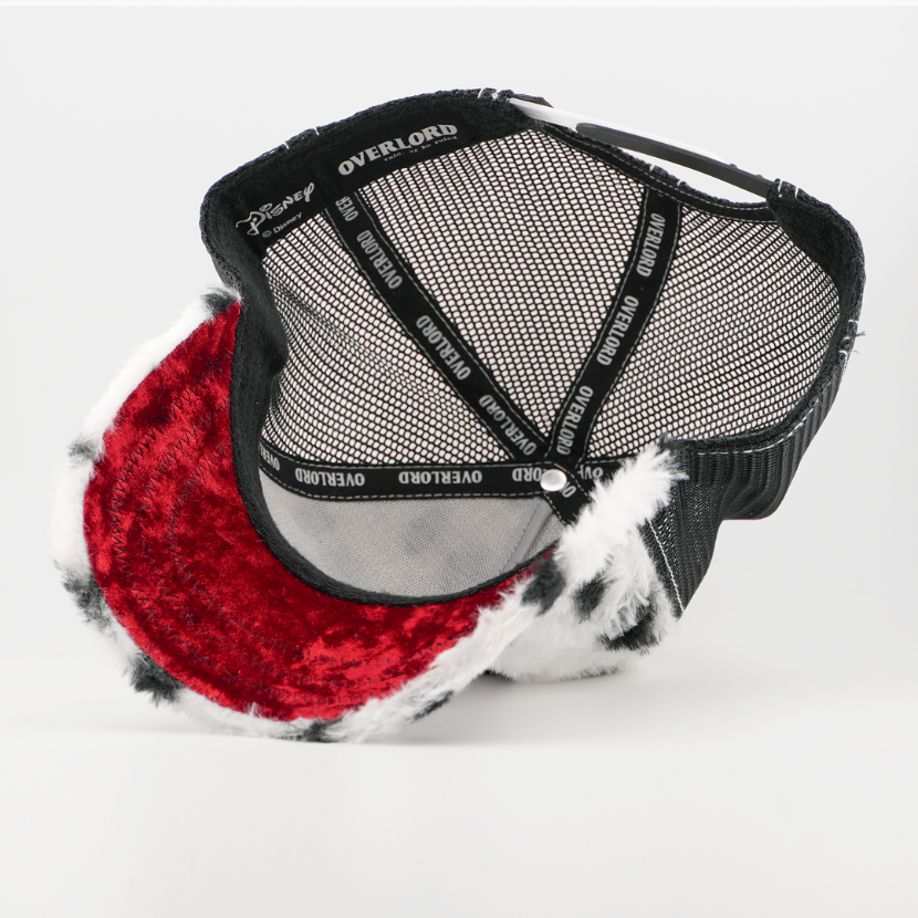 Underside of the Cruella de Vil retro trucker cap showing a red velvet brim, Disney tag, black mesh crown, and black Overlord taping.