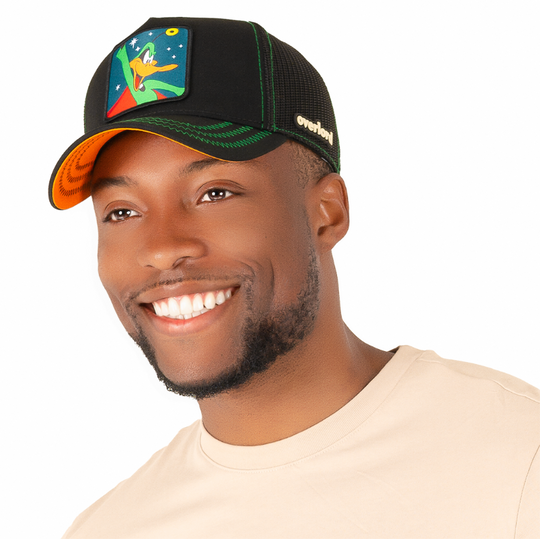 Man wearing black twill trucker cap with black mesh featuring a woven patch of Daffy Duck as Duck Dodger attached to the crown.