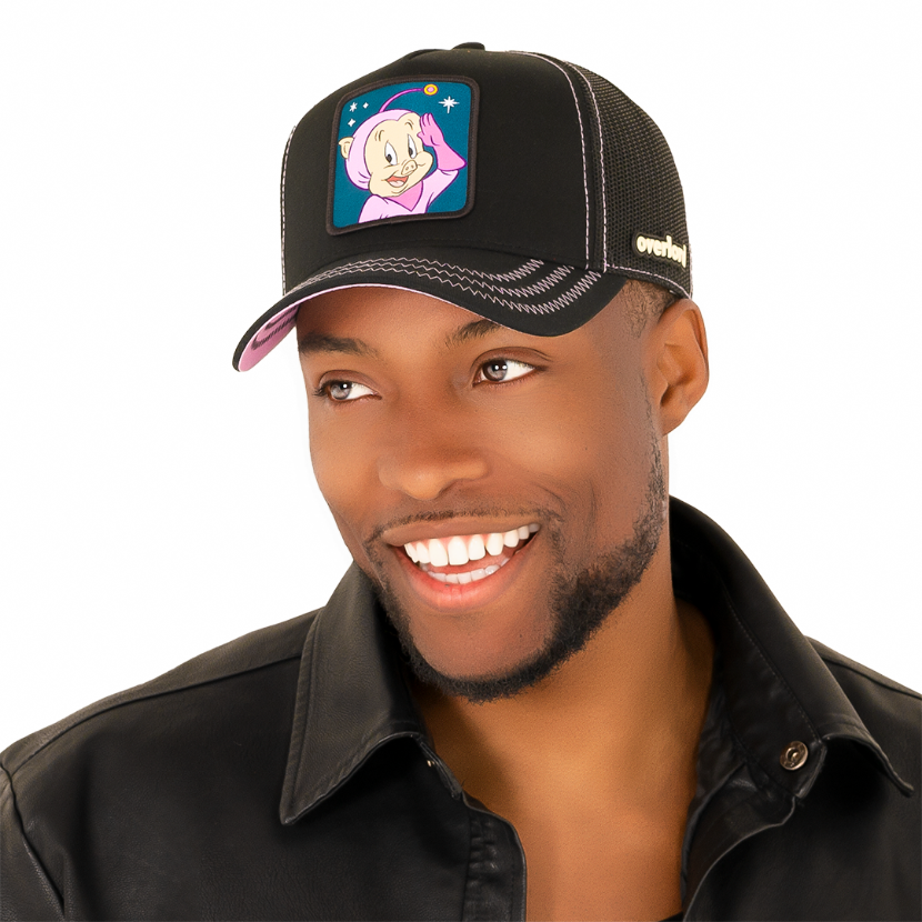 Man wearing black twill trucker cap with black mesh featuring a woven patch of Porky Pig as the Space Cadet attached to the crown.