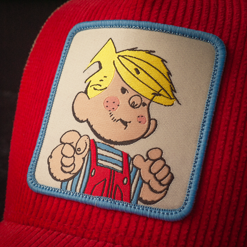 Close-up of Dennis the Menace woven patch on red corduroy trucker cap hat